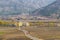 Two Buddhist monks in traditional red clothes walk along the road to the village. Mountains of the Himalayas on the horizon.