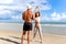 Two buddy doing body stretching exercises outdoor on summer tropical island beach with blue sea, couple doing exercise outdoor,