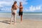 Two buddy doing body stretching exercises outdoor on summer tropical island beach with blue sea, couple doing exercise outdoor,