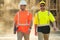 Two builders in a hard hat is busy working on a construction project at a site. A builders workes in a helmet near