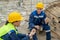 Two builders in hardhats and workwear having sandwiches with tea