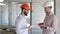 Two builders looking at the digital tablet at the building under construction