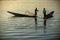 Two Burmese men paddle their legs Came out to find fish in the morning on Inle Lake