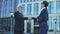 Two business people shaking hands outdoors, merger and acquisition agreement