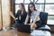 Two business woman sit on sofa and see document on hand and computer on the table