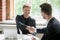 Two businessmen handshaking at negotiating meeting in office wit