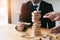 Two businessmen help to hold the wood block to fall down