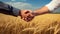 Two businessmen in a jacket and shirt shake hands while concluding a grain and wheat trade close-up, next to a wheat