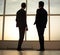 Two businessmen look at the city from the window of the business center