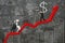 Two businessmen moving dollar sign upward on red trend chart