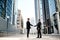 Two businessmen shaking hands on background office corporate buildings