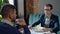 Two businessmen is talking during business lunch, sitting at table in cafe.