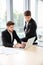 Two businessmen using laptop in office together