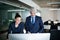 Two businesspeople with computer in an office standing at desk.