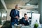 Two businesspeople with computer sitting in an office at desk.