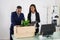 Two Businesspeople Packing Plant And Folders In Cardboard Box