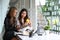 Two businesswomen analyzing documents while sitting together in modern office.