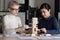 Two businesswomen build tower of wooden blocks play build game