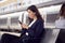 Two Businesswomen Commuting To Work Waiting For Train On Station Platform Looking At Mobile Phones