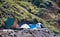Two camping tents set up on the slope of a green valley and a small summer bungalow