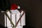 two candy canes and a red Christmas hat with a pompom on a white decorative fence, brown beige background