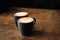 Two cappuccino coffee with latte art on wooden table. Black cups and beautiful milk foam. Soft focus