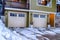 Two car garage with glass panes on the white doors under balcony and windows