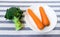 Two Carrots on White Plate with Green Broccoli on Blue and White