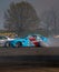 two cars on an auto race track in the air as the smoke drifts