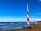 Two catamarans with red and white sails, standing on the beach sand.