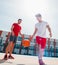 Two caucasian basketball player fighting for ball possession at the basketball court on a sunny day