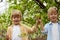 Two caucasian blonde kids boys stand among trees together