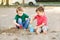 Two Caucasian children sitting in sandbox playing with beach toys. Little boys friends having fun together on a playground. Summer