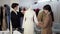 Two caucasian female tailors collaborating on white wedding dress and pinning unfinished garment on mannequin in fashion