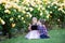 Two Caucasian kids sitting on a green grass in a rose garden and hugging, brother and sister, siblings,