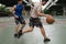 Two caucasian men pratice baskegball in court at urban street