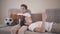 Two Caucasian schoolboys resting at home on the sofa. Twin brothers in similar clothes reading indoors. One boy using