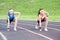 Two Caucasian Sportswomen in Professional Sportsgear Standing Prepared to Run On Sport Venue Outdoors