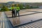 Two Caucasian technician workers stand on rooftop and discuss about the maintenance solar cell panels on rooftop of factory or the