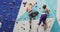 Two caucasian women climbing up a wall side by side at indoor climbing wall