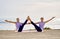 Two caucasian women doing yoga exercise twisted boat pose near the sea