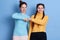 Two caucasian women fist bumping against blue wall, two friends greeting, females wearing casual shirts, have dark hair,