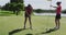 Two caucasian women playing golf one taking shot from bunker