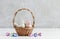 Two ceramic birds in wicker Easter basket. Eggs around, grey stone background