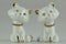 Two ceramic cat figurines with glass eyes and golden collars.