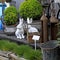 Two ceramic hares among boxwood bushes and garden grass. Trolley on wheels and miscellaneous gardening utensils - lanterns