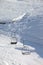 Two chair-lift with snowdrift and off-piste slope in sun morning