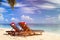 Two chair lounges with red Santa hats on tropical