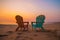 Two chairs on the beach at sunrise or sunset time with copy space. Travel content.