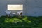 Two Chairs, Table and Water Glasses Near Window with Bright Sun Light Shining Through Concrete Wall in Grass and Rocks Field